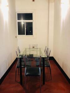 een glazen tafel en stoelen in een kamer met een raam bij R & D Resort in Polonnaruwa