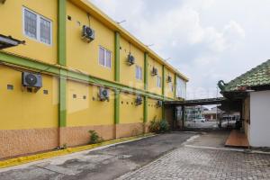 a yellow and green building with a street at Homestay Hj Suharti Natar Lampung RedPartner in Negarasaka