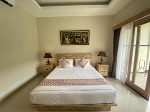 een slaapkamer met een groot bed met 2 nachtkastjes bij Green D'Mel Luxury Homestay in Nusa Dua