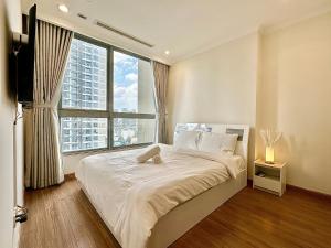 una camera da letto con un grande letto con una grande finestra di Vinhomes Landmark Apartment - CirillaHome ad Ho Chi Minh