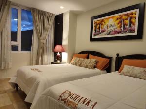 a bedroom with two beds and a painting on the wall at Chanka Suites in Talavera