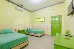 Negarasaka的住宿－Homestay Hj Suharti Natar Lampung RedPartner，一间卧室配有两张床、一张桌子和一台电视。
