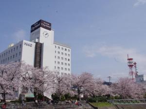 un gran edificio blanco con una torre de reloj y árboles en Tottori City Hotel / Vacation STAY 81349, en Tottori
