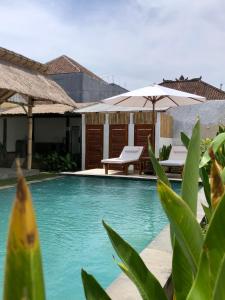 a swimming pool with an umbrella and a table and chairs at NOMAD Tropical Hostel Canggu in Dalung