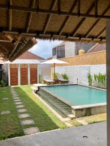a swimming pool with a table and an umbrella at NOMAD Tropical Hostel Canggu in Dalung