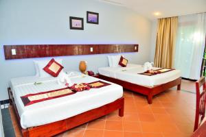 a bedroom with two beds and two chairs at Thai Hoa Mui Ne Resort in Mui Ne