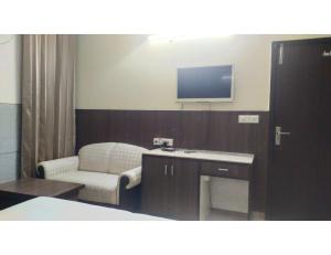 Zimmer mit einem Stuhl, einem Schreibtisch und einem TV in der Unterkunft HOTEL HILROZ, PUNJAB in Amritsar