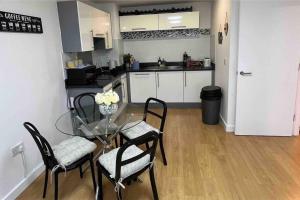 a small kitchen with a glass table and chairs at Cosy & sweet, 1bd Spacious By Media City in Manchester