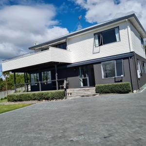 une grande maison blanche avec une allée. dans l'établissement Wharewaka Haven, à Taupo