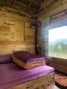 Bett in einer Holzhütte mit Fenster in der Unterkunft Y Bé Homestay, Kon Vơng Kia, Măng Đen 