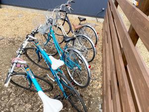 drei Fahrräder, die neben einem Holzzaun geparkt sind in der Unterkunft CAMP＆COTTAGE THE DOOR in Fujikawaguchiko