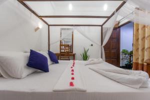 Una gran cama blanca con una cinta roja. en Chimaca Bay Hotel, en Arugam Bay