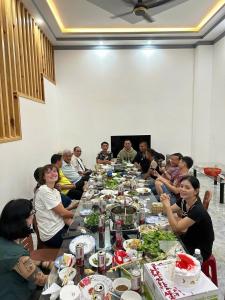 a group of people sitting around a long table with food at Lak village in Lien Son