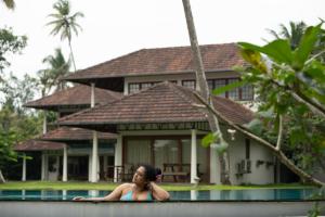 a woman standing in a pool in front of a house at Cranganor History Café & Riverside Château in Parūr