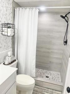 a bathroom with a white shower curtain and a toilet at A Mid Somerset Dream in West Kelowna