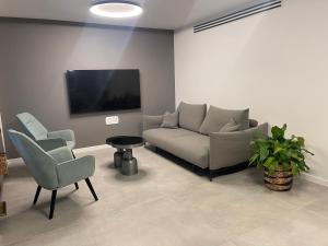 een woonkamer met een bank, 2 stoelen en een tv bij Netanya-Appartement - 5p in Netanya