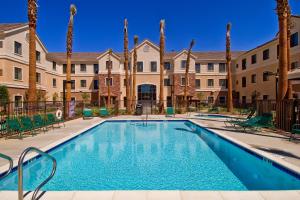 una piscina con palmeras y edificios en Staybridge Suites Palmdale, an IHG Hotel, en Palmdale