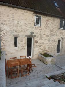 un patio con mesas y sillas frente a un edificio de piedra en Maison de village rénovée, en Meyronne