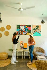 deux femmes debout dans une pièce en train de regarder un tableau dans l'établissement Locomo Boutique, Morjim - Stay Work Eat, à Morjim