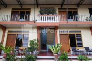 a building with a balcony with chairs and plants at Hotel Sido Langgeng Tawangmangu Mitra RedDoorz in Karanganyar