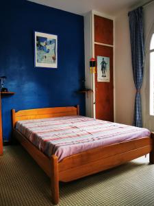 1 dormitorio con cama de madera y pared azul en Large family house close to the beach en Les Mathes
