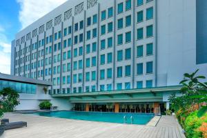 a hotel with a swimming pool in front of a building at Five Premiere Hotel in Samarinda