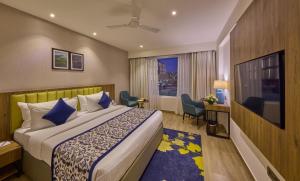 um quarto de hotel com uma cama e uma televisão em Grand Continent Hebbal A Sarovar Portico Affiliate Hotel em Bangalore