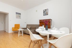 sala de estar con mesa blanca y sillas en One-Bedroom Capital Apartment by Renters, en Varsovia