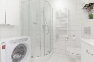 a white bathroom with a washing machine in a shower at One-Bedroom Capital Apartment by Renters in Warsaw