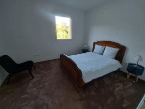 een slaapkamer met een bed, een stoel en een raam bij Maison calme à la campagne 