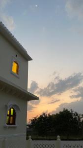 a building with a window with a sunset in the background at Dera Padlia - A Rural Experience Farm Stay 
