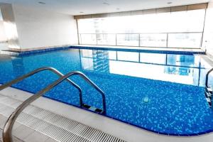 a large swimming pool with blue water in a building at Citi home 1BR New Marina Sulafa Tower in Dubai