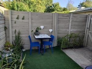 a table and chairs in a backyard with a fence at Stonehenge Cottage in Oudtshoorn