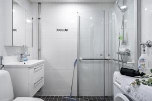 un bagno bianco con doccia e lavandino di Hiisi Homes Porvoo Toukovuori a Porvoo Altre 47 foto