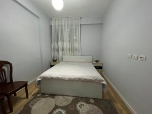 a bedroom with a bed and a chair and a window at SALA Apartment in Shkodër