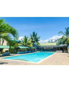 ein Pool mit Palmen und ein Gebäude in der Unterkunft ASINS HOLIDAY INN HOTEL in Ukunda