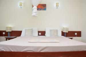a bedroom with a white bed with two lamps at ASINS HOLIDAY INN HOTEL in Ukunda