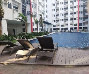 a swimming pool with two chairs next to a building at Bloom Residences Condo 2Br in Manila