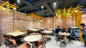 three men sitting at tables in a brick restaurant at Travellers Hotel in New Delhi