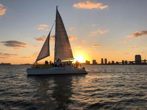 a sailboat in the water with the sunset in the background at Mariah Catamaran in Miami Beach