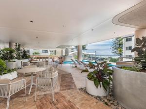 a restaurant with tables and chairs and a pool at Hemingway Palm Beach - Premium Oceanview Apartments in Gold Coast