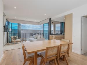 a kitchen and living room with a table and chairs at Hemingway Palm Beach - Premium Oceanview Apartments in Gold Coast