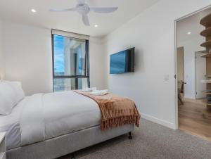 a white bedroom with a bed and a window at Hemingway Palm Beach - Premium Oceanview Apartments in Gold Coast