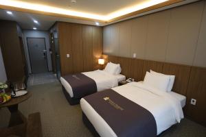 Habitación de hotel con 2 camas y mesa en Benikea hotel seosan en Seosan
