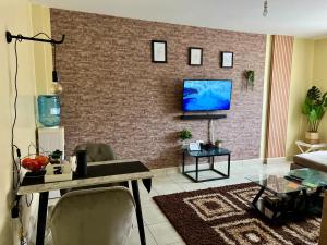 a living room with a tv on a brick wall at Eclectic 2 bedrm homely & comfy in Machakos