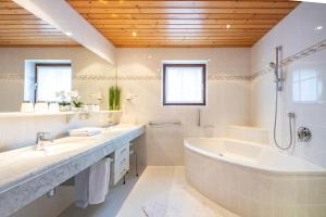 ein weißes Badezimmer mit einer Badewanne und einem Waschbecken in der Unterkunft Frühstückspension-Appartementhaus Wasserer in Bad Kleinkirchheim