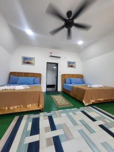 two beds in a room with a ceiling fan at DEWATI ROOMSTAY B&B in Lang Tengah