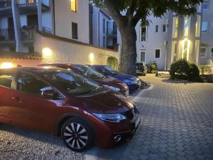eine Reihe geparkter Autos neben einem Gebäude in der Unterkunft Benevia Apartments in Pécs