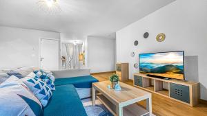 uma sala de estar com um sofá azul e uma televisão de ecrã plano em COLOC LAGON - Belle Colocation haut de gamme de 3 chambres / Proche Gare / Parking gratuit / Balcon / Wifi & Netflix em Ville-la-Grand