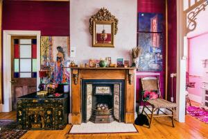 a living room with a fireplace and a wall with paintings at Chinoiserie - Blue Mountains Boho Luxe in Katoomba